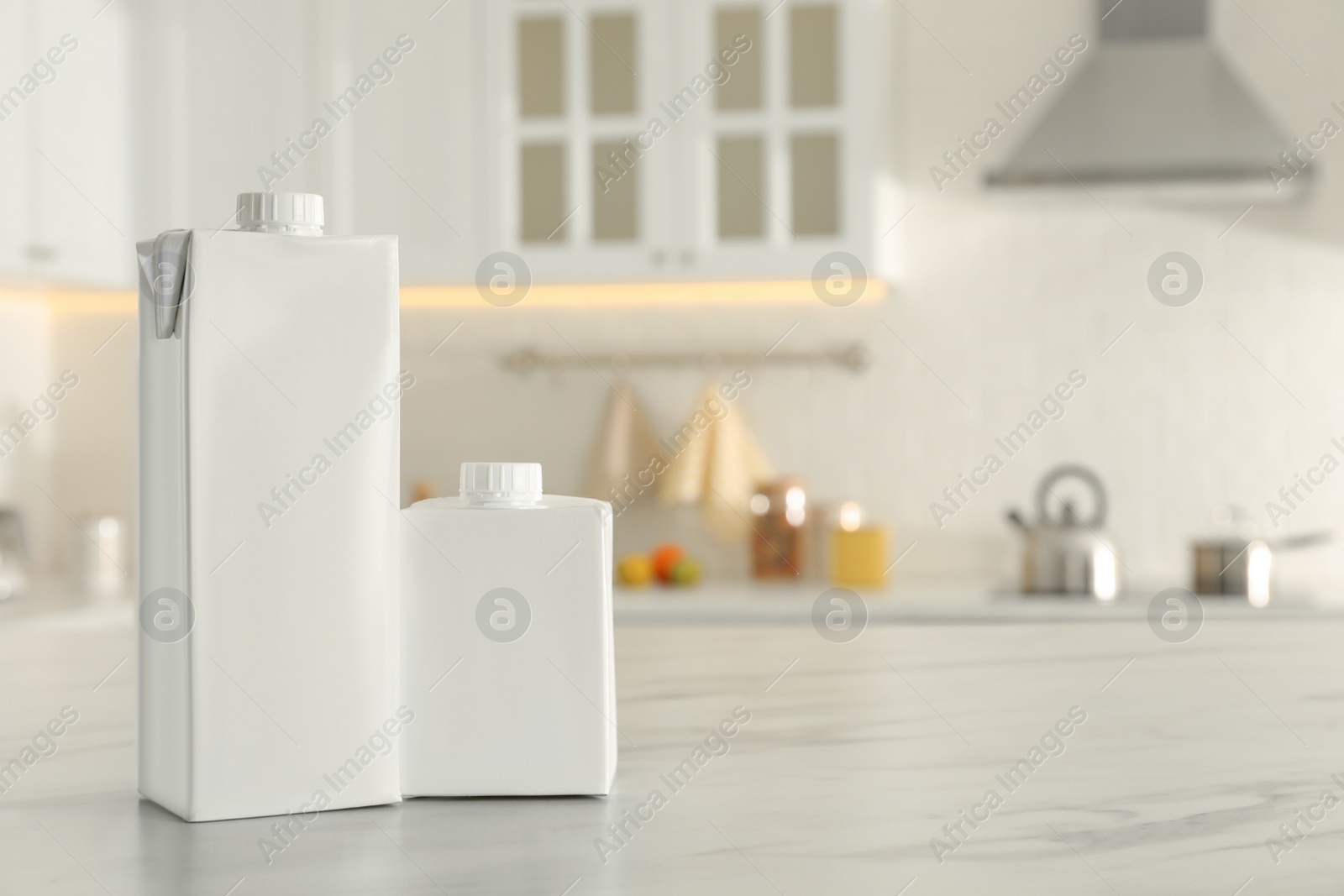 Photo of Carton boxes of milk on table in kitchen, space for text