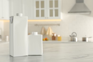 Photo of Carton boxes of milk on table in kitchen, space for text