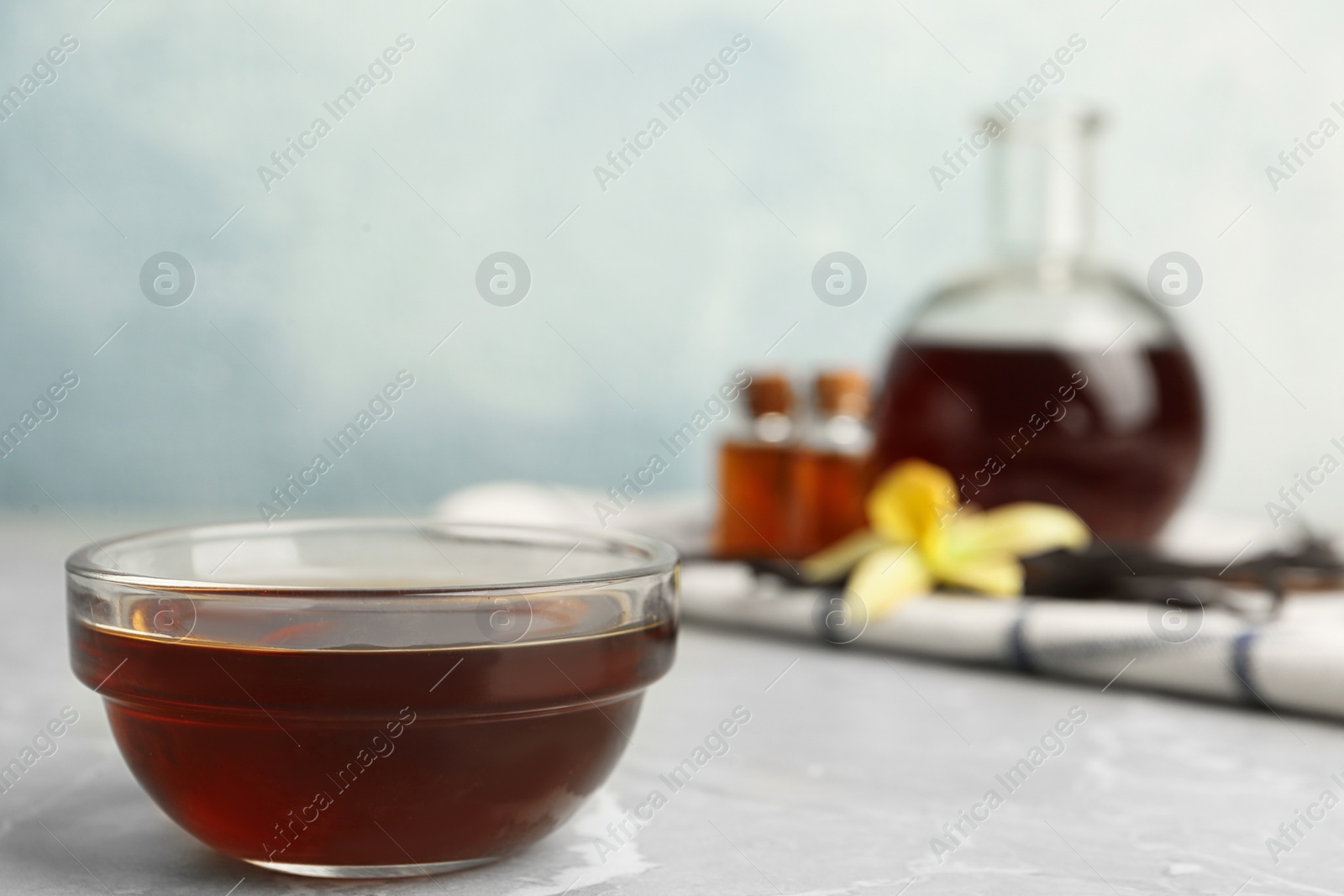 Photo of Aromatic homemade vanilla extract on light grey marble table. Space for text