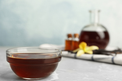 Photo of Aromatic homemade vanilla extract on light grey marble table. Space for text