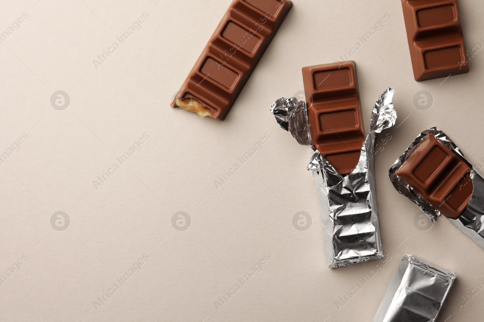 Photo of Tasty chocolate bars on light background, flat lay. Space for text