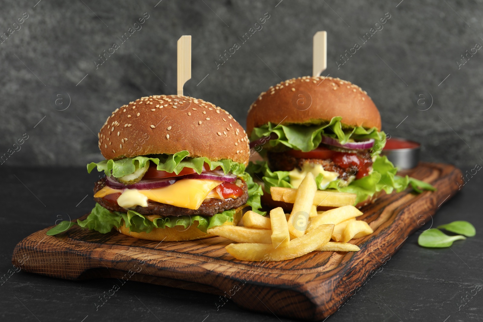Photo of Delicious burgers with beef patty and french fries on dark table