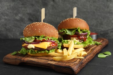 Delicious burgers with beef patty and french fries on dark table