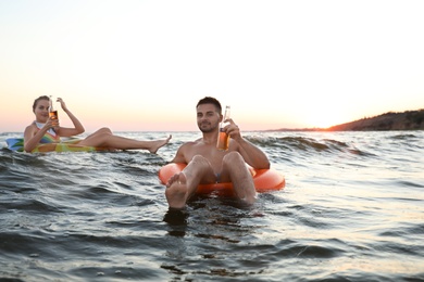 Photo of Happy young couple on inflatable rings in water