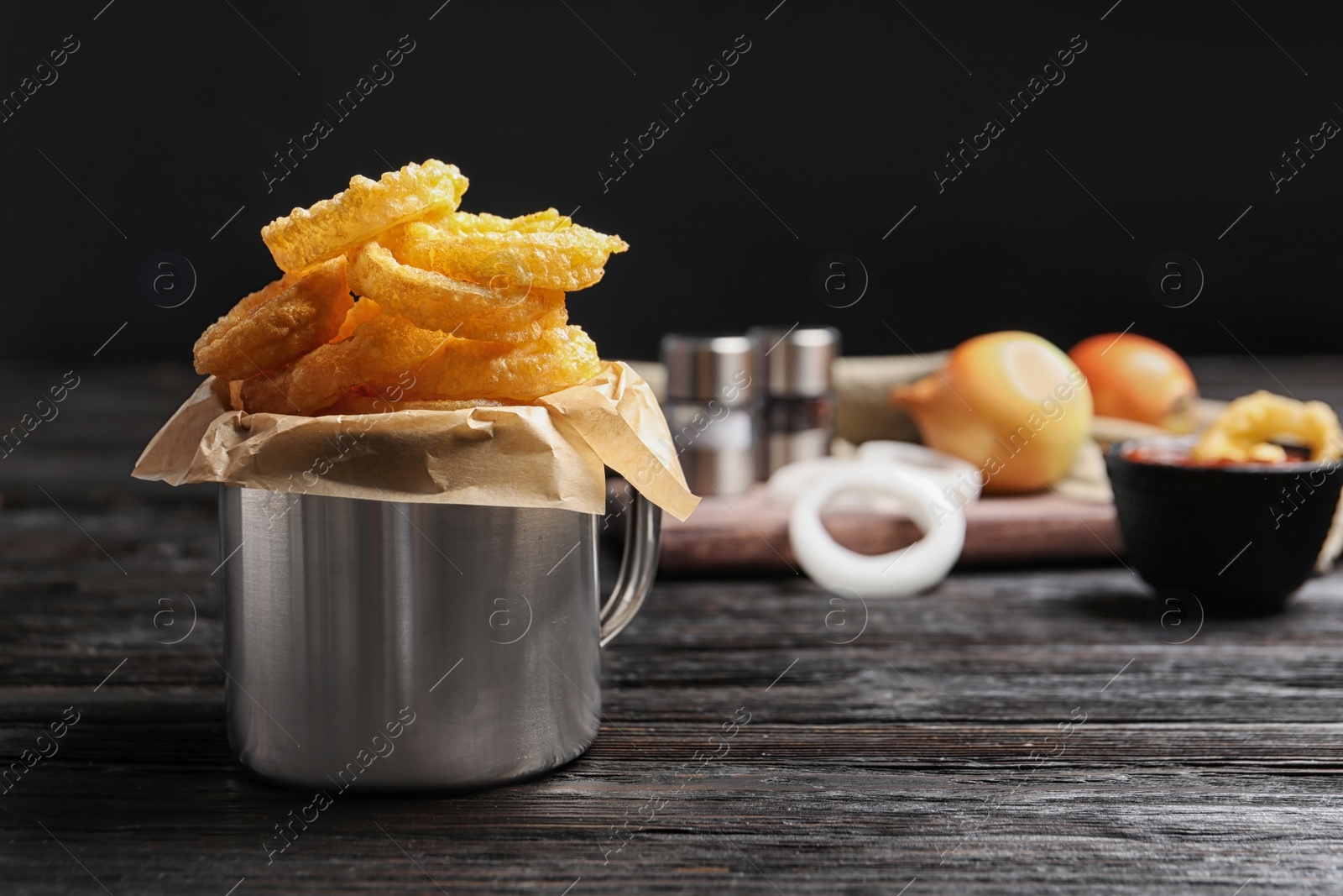 Photo of Dishware with homemade crunchy fried onion rings on wooden table. Space for text