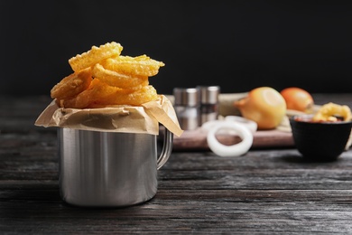 Photo of Dishware with homemade crunchy fried onion rings on wooden table. Space for text