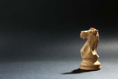 Photo of White wooden chess knight on dark background. Space for text