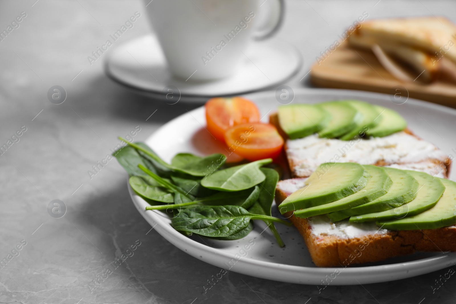 Photo of Sandwiches with avocado and spinach served on grey  table, closeup