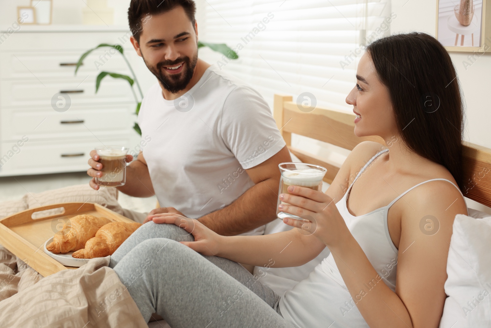 Photo of Happy couple having breakfast on bed at home