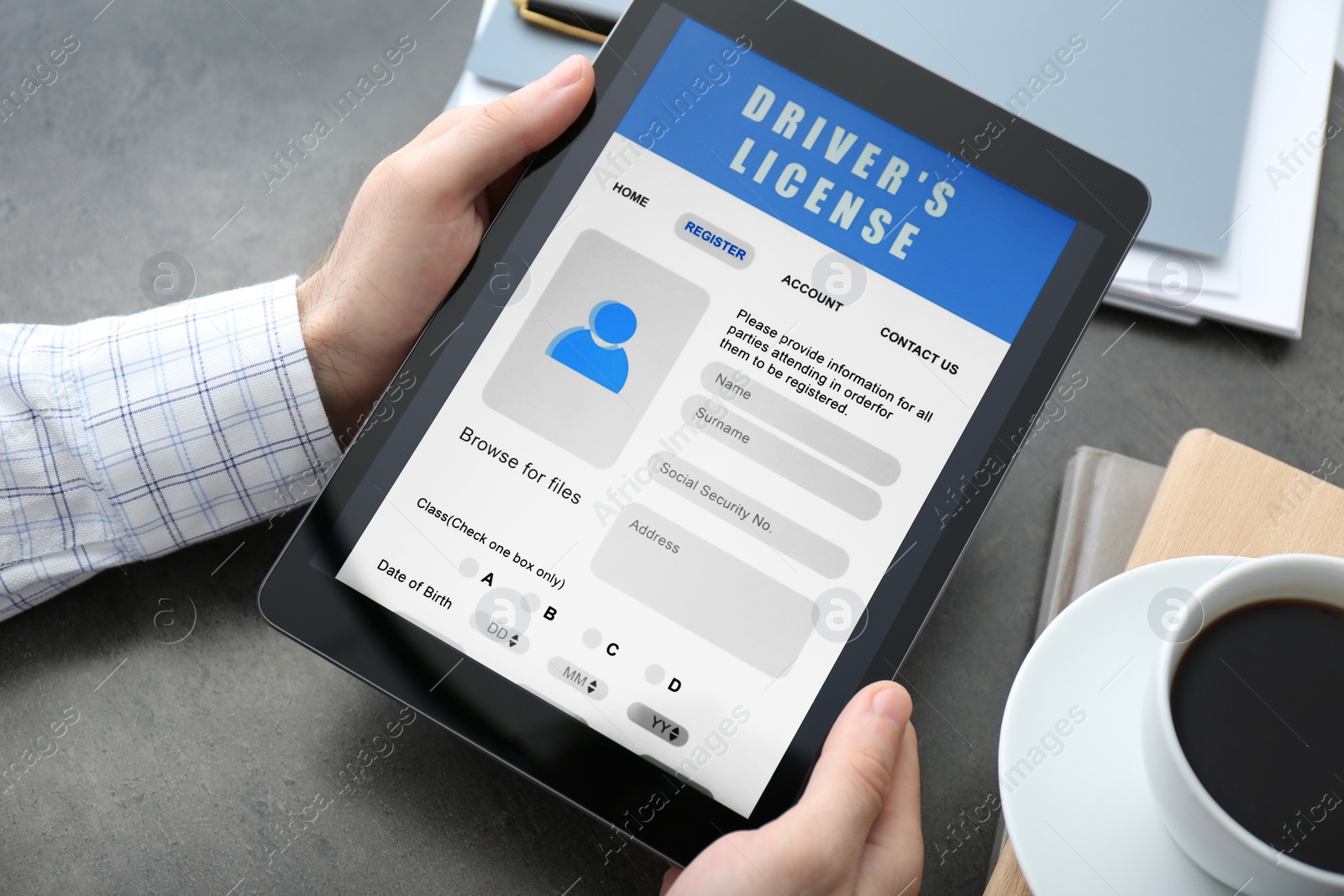 Photo of Man holding tablet with driver's license application form at grey table, closeup