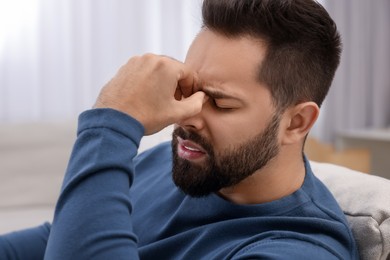 Unhappy man suffering from headache at home