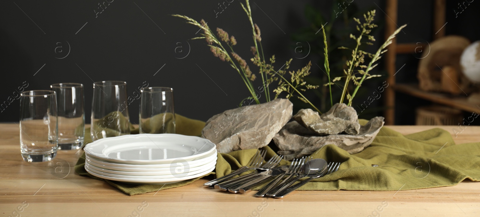 Photo of Clean dishes, stones and plants on wooden table in dining room