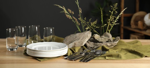 Clean dishes, stones and plants on wooden table in dining room