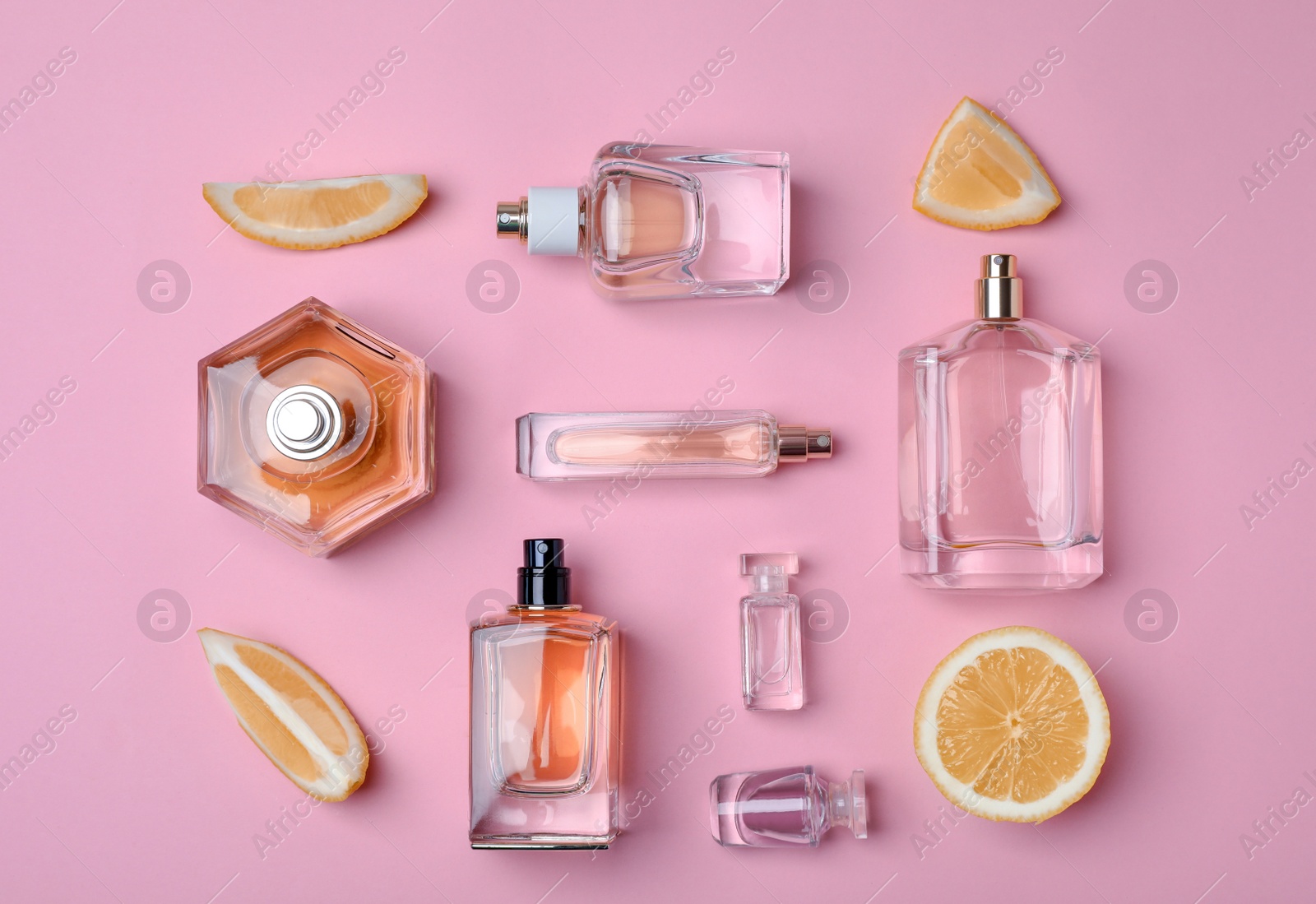 Photo of Bottles of perfume and lemon on color background, top view