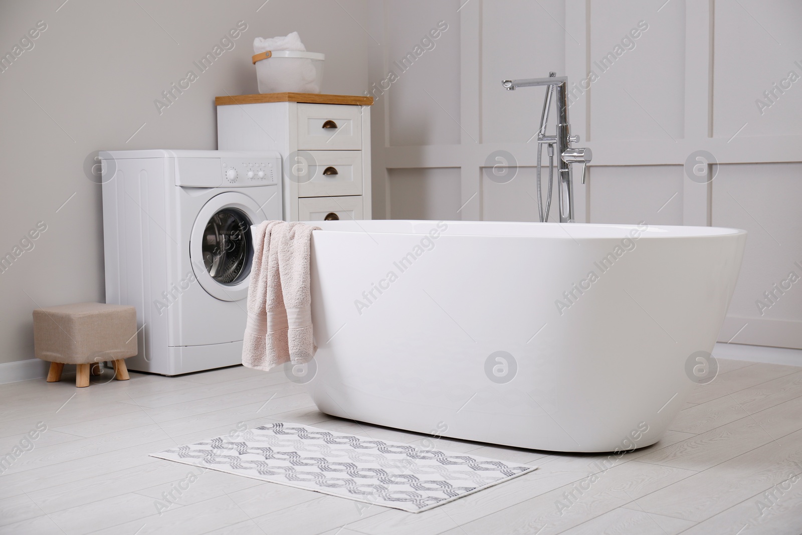 Photo of Stylish mat on floor near tub in bathroom. Interior design