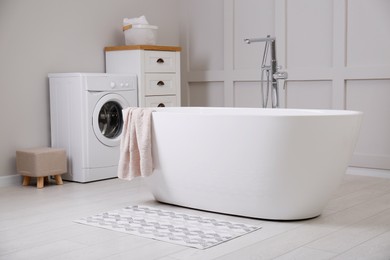 Stylish mat on floor near tub in bathroom. Interior design