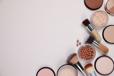 Different face powders and makeup brushes on light background, flat lay. Space for text