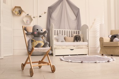 Photo of Buggy with elephant toy in baby room, space for text. Interior design