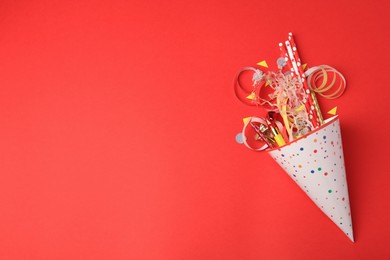 Party hat and different festive items on red background, flat lay. Space for text