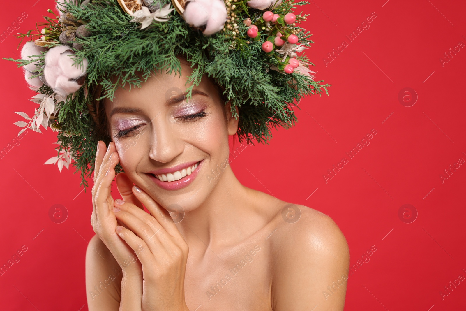 Photo of Happy young woman wearing wreath on red background