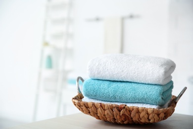 Photo of Wicker tray with towels on table against blurred background