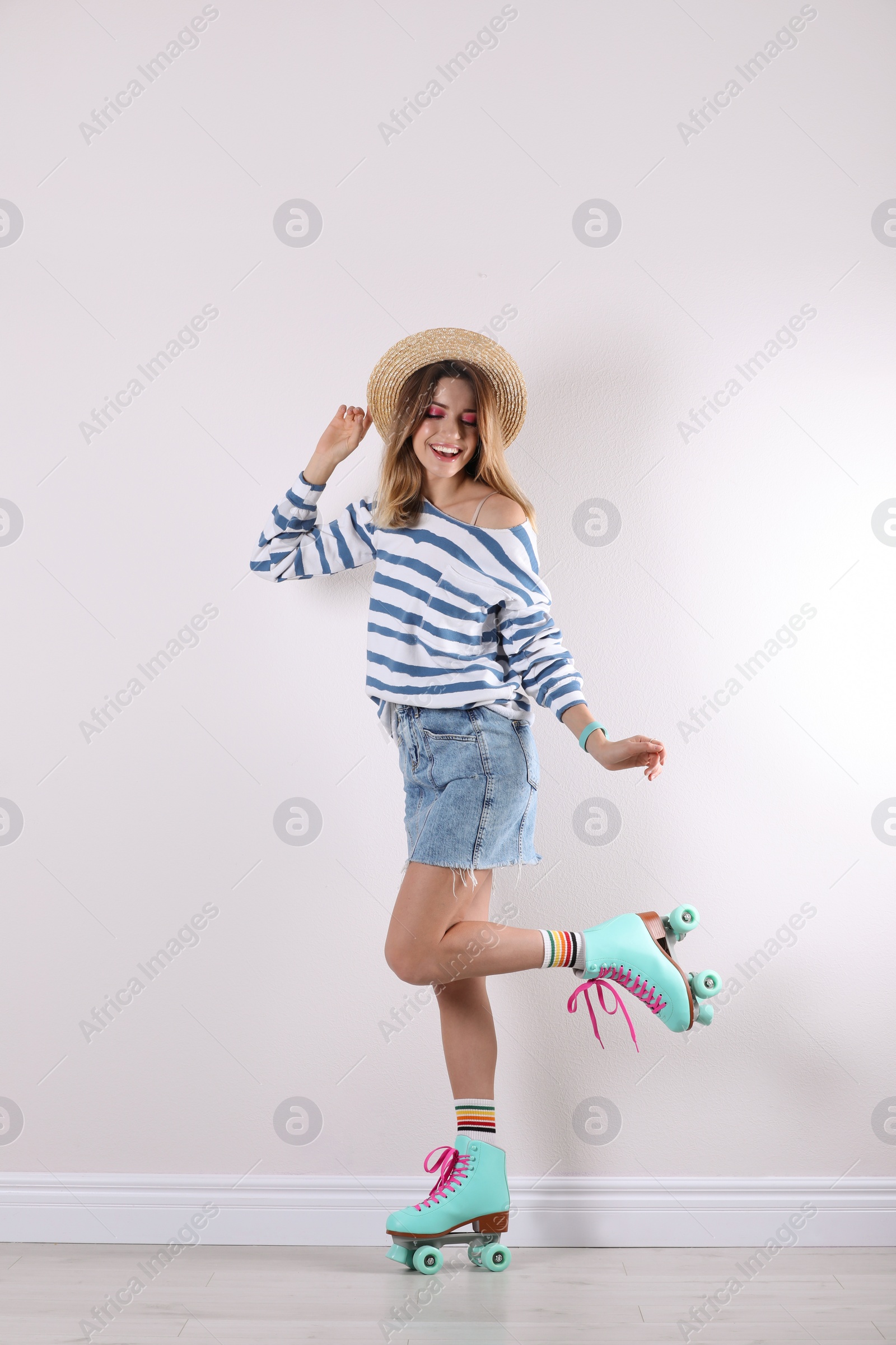 Photo of Young woman with retro roller skates near white wall