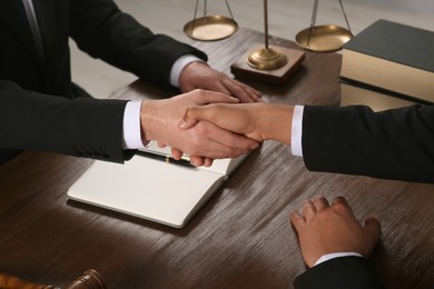 Photo of Law and justice. Notary with client shaking hands at wooden table, closeup