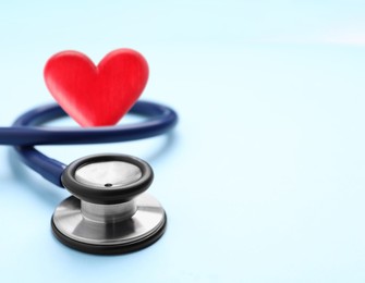 Image of Stethoscope and red heart on light blue background, space for text 