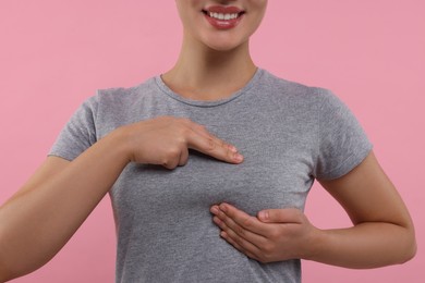 Woman doing breast self-examination on pink background, closeup