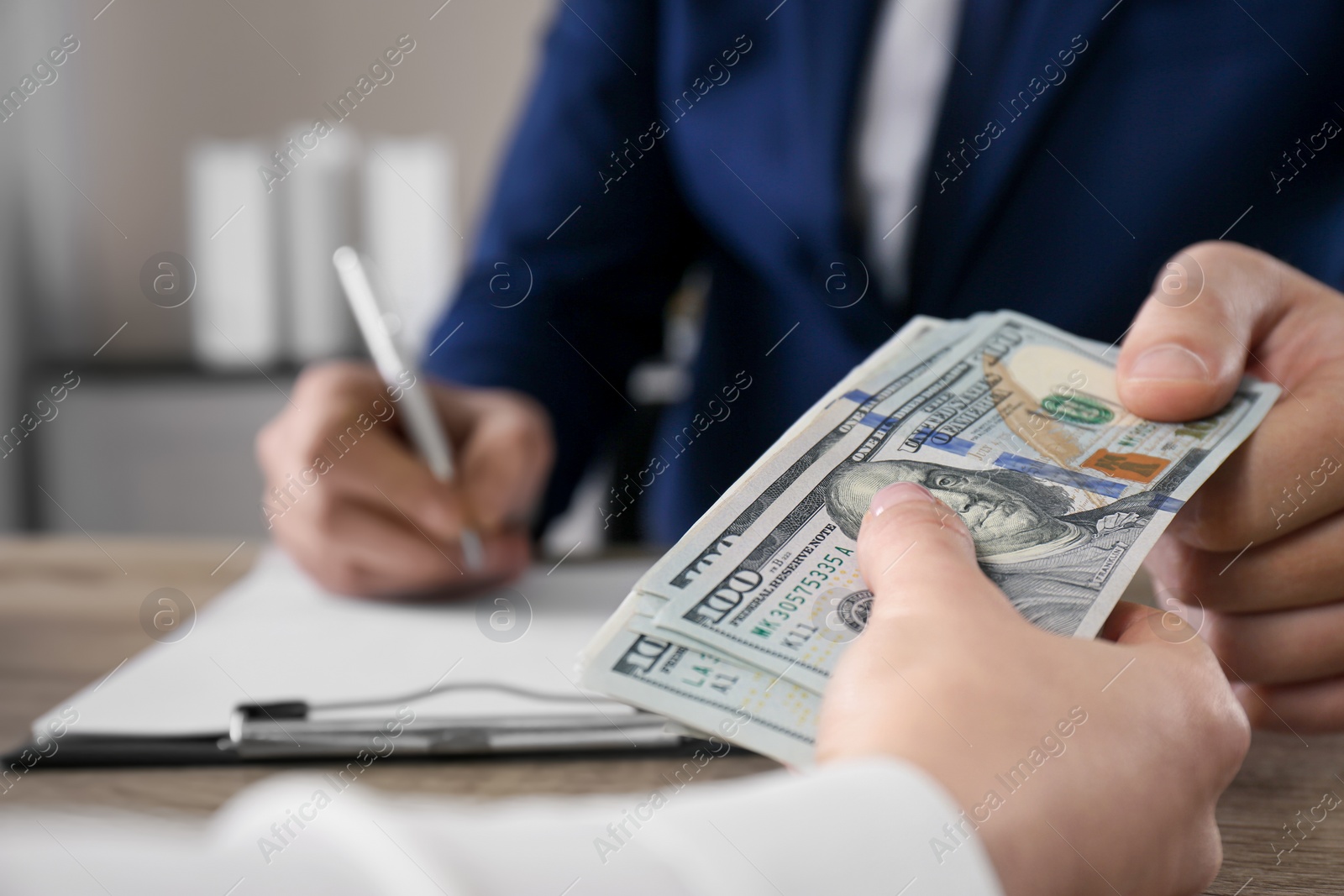 Photo of Woman giving bribe to man at table in office, closeup