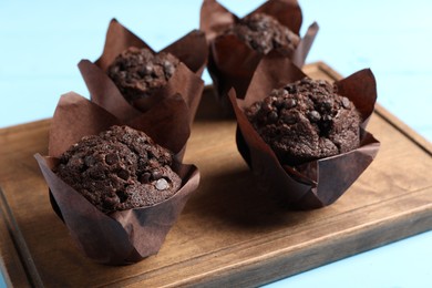 Tasty chocolate muffins on light blue table, closeup