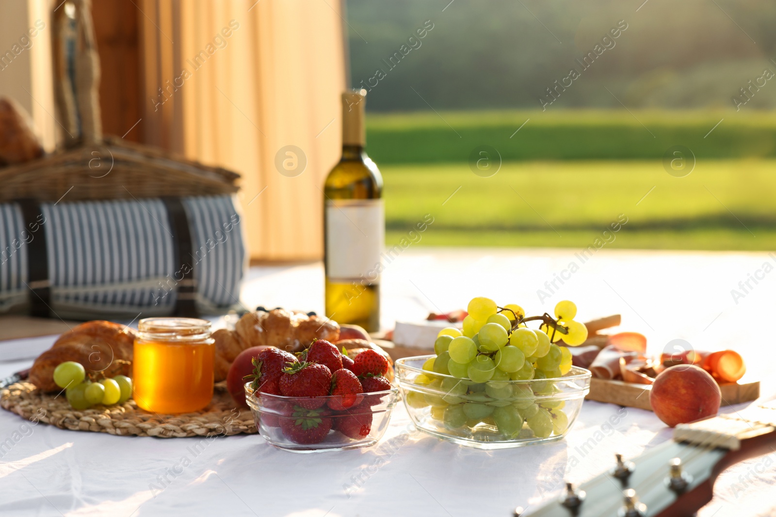 Photo of Romantic date. Delicious snacks for picnic on white blanket outdoors