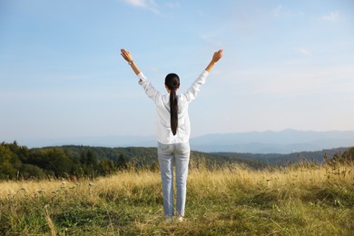 Photo of Feeling freedom. Woman with wide open arms on meadow, back view