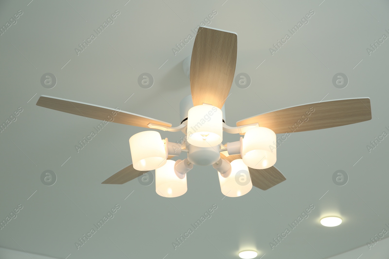 Photo of Ceiling fan with lamps indoors, low angle view