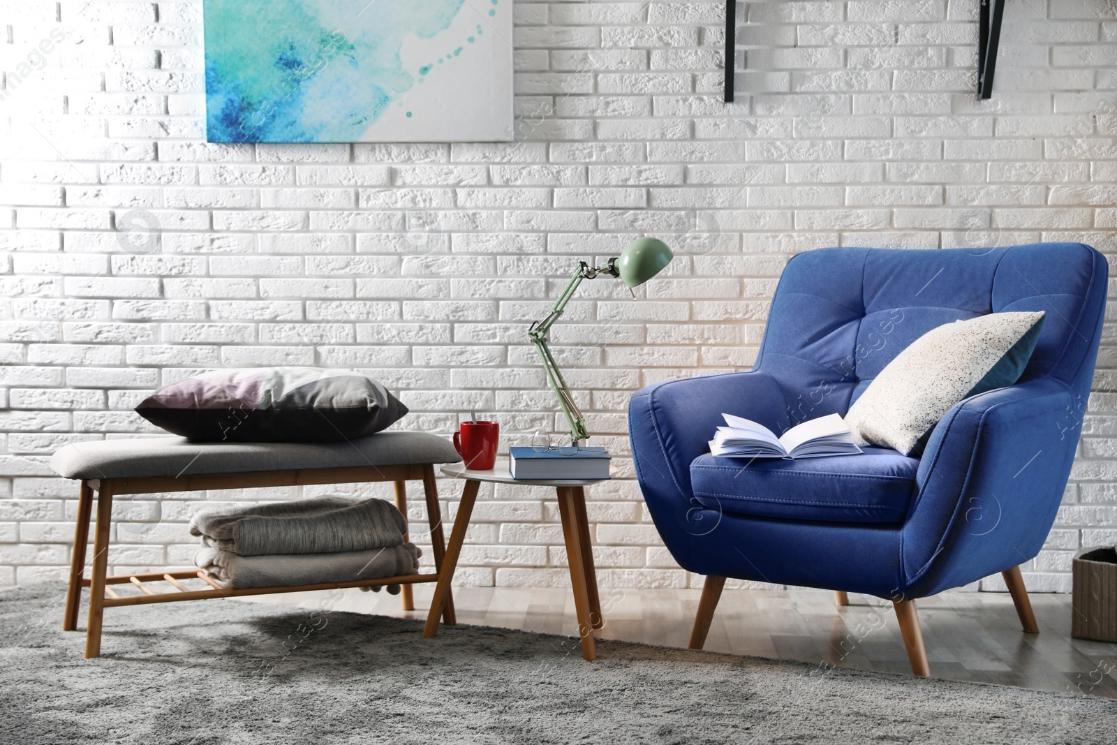 Photo of Room interior with comfortable furniture and books near brick wall