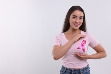 Photo of Beautiful young woman with pink ribbon on white background, space for text. Breast cancer awareness