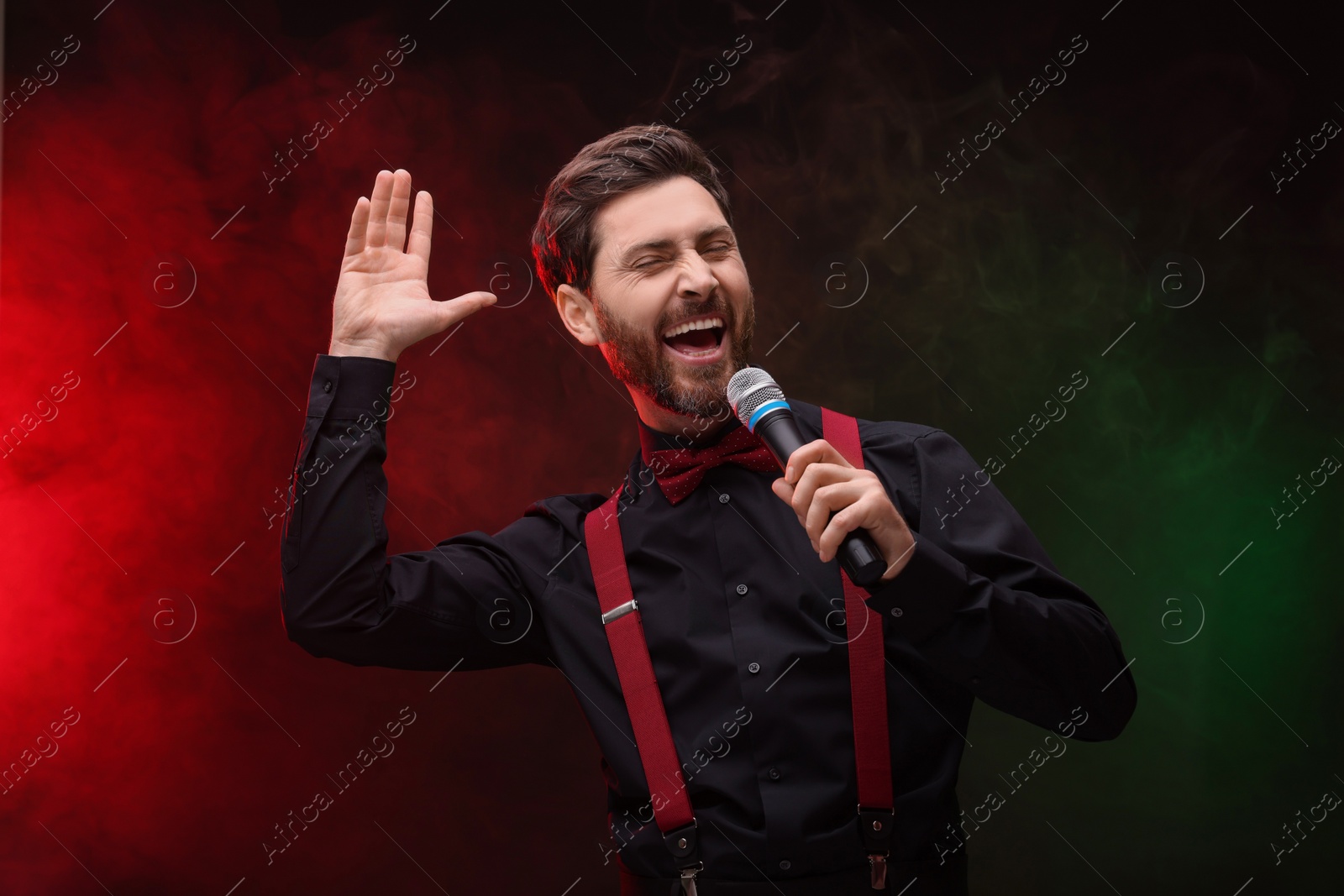 Photo of Emotional man with microphone singing in color lights