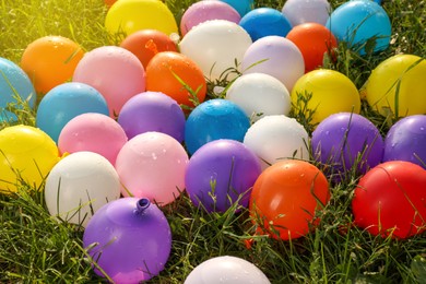 Lots of colorful water bombs on green grass outdoors