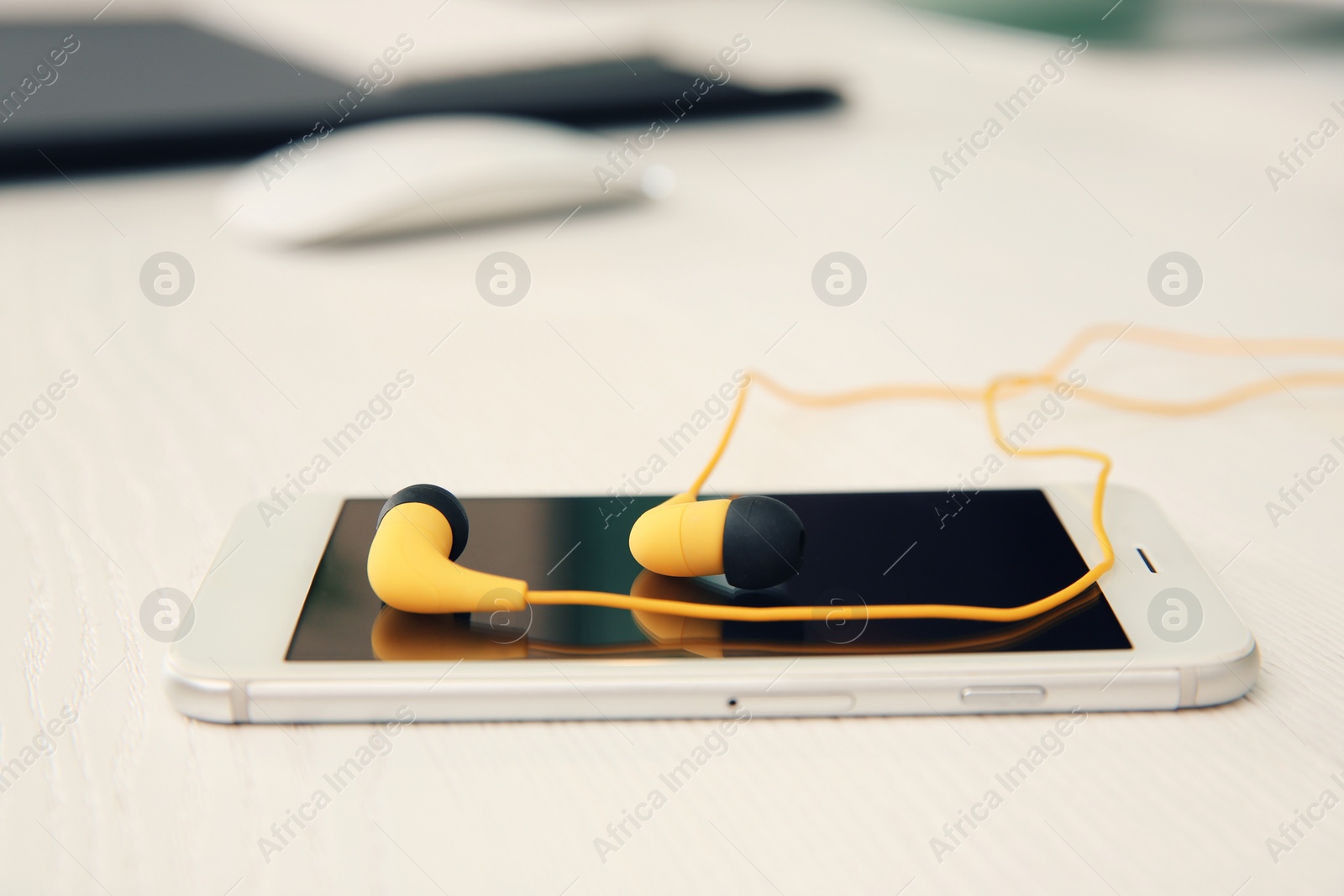 Photo of Smartphone with headphones on white table. Space for text