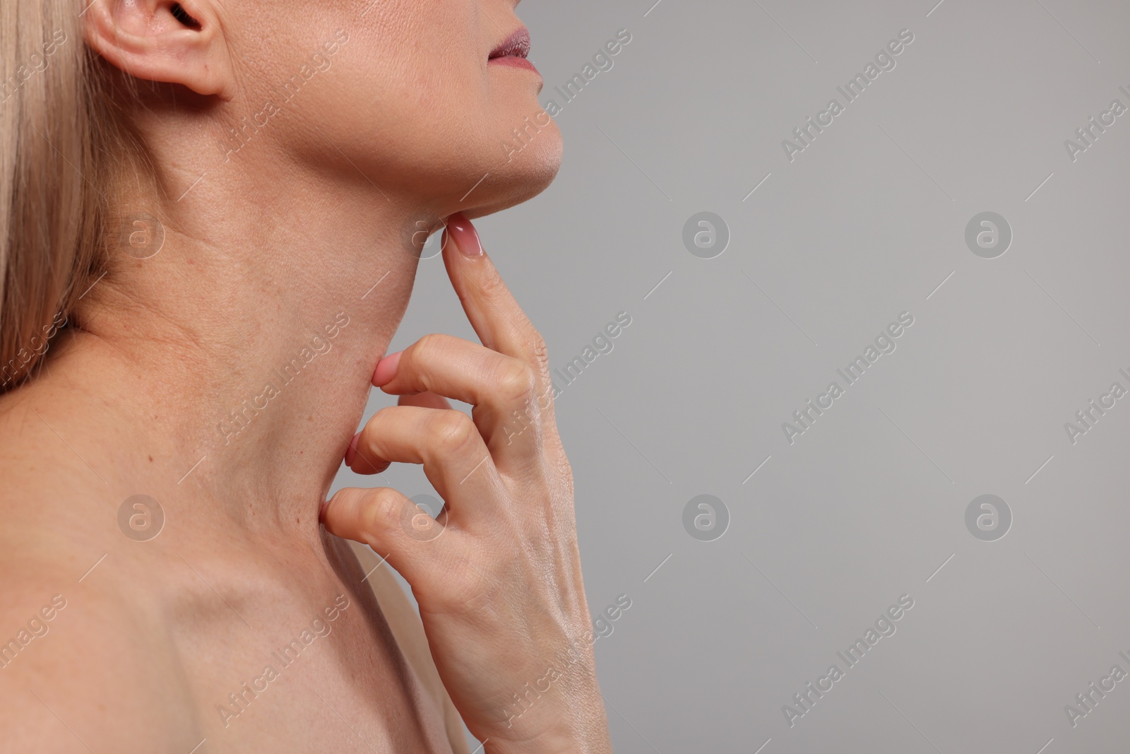 Photo of Woman touching her neck on grey background, closeup. Space for text