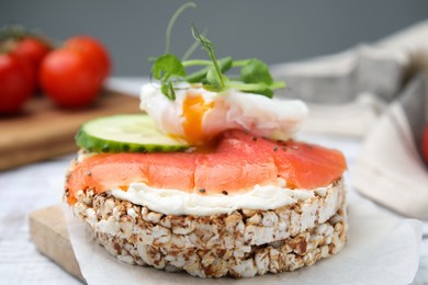 Photo of Crunchy buckwheat cakes with salmon, poached egg and cucumber slices served on board, closeup