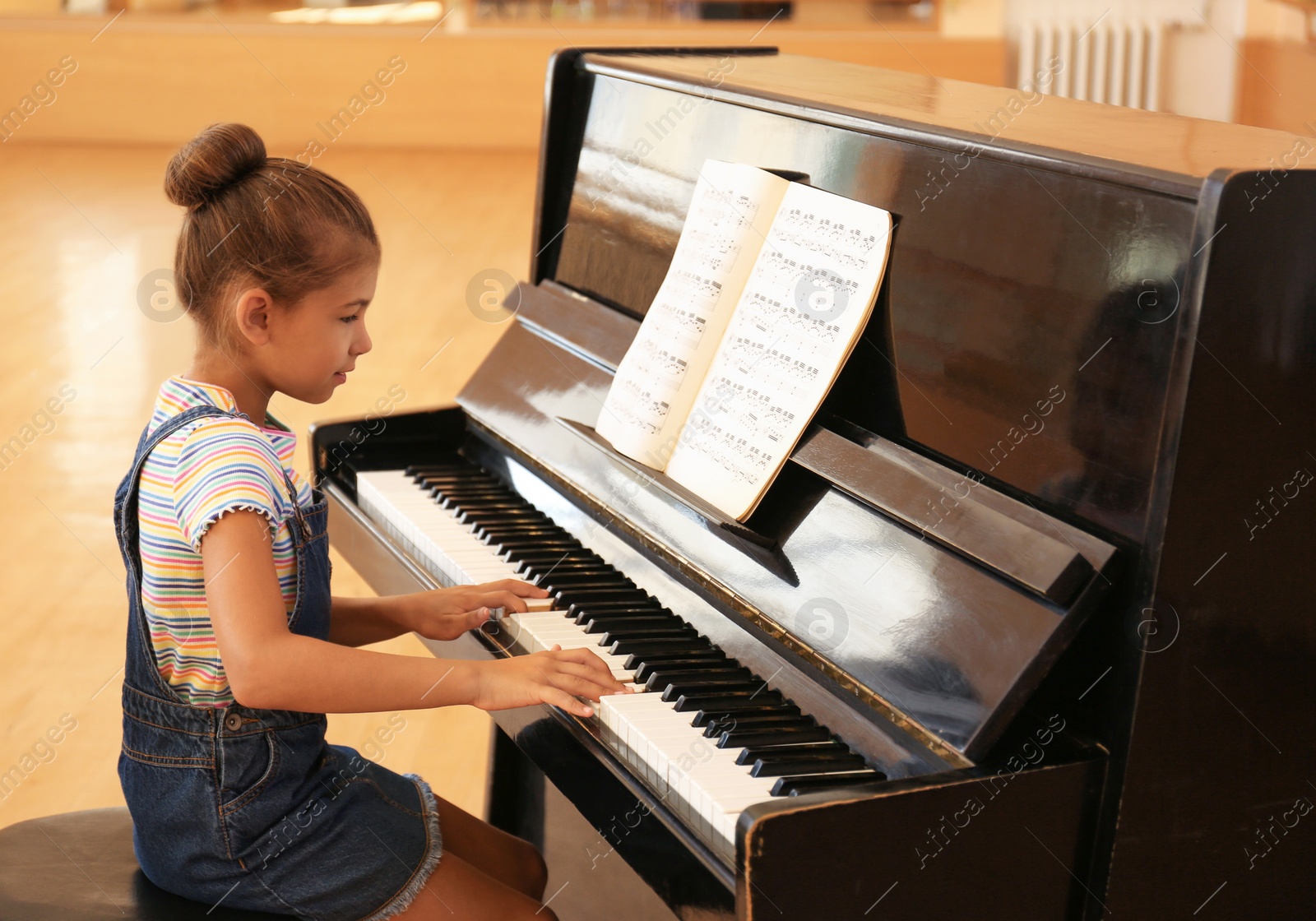 Photo of Cute little girl playing piano indoors. Music lesson