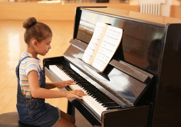 Cute little girl playing piano indoors. Music lesson