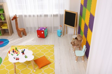 Child`s playroom with different toys and furniture, above view. Cozy kindergarten interior