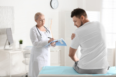 Photo of Female orthopedist examining patient with injured arm in clinic