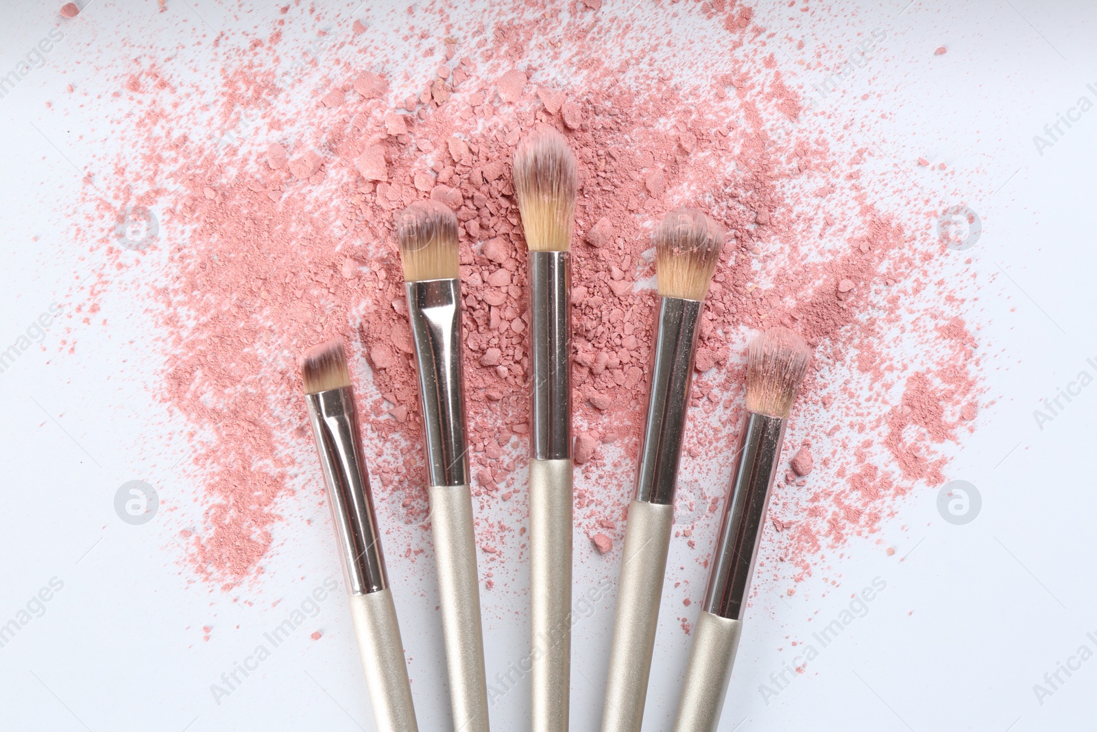 Photo of Makeup brushes and scattered eye shadow on white background, flat lay