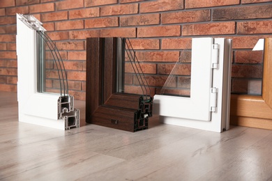 Photo of Samples of modern window profiles on floor against brick wall. Installation service