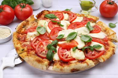 Photo of Delicious Caprese pizza with tomatoes, mozzarella and basil served on white tiled table, closeup