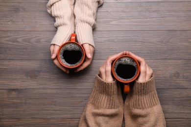 Women with cups of coffee at wooden table, top view