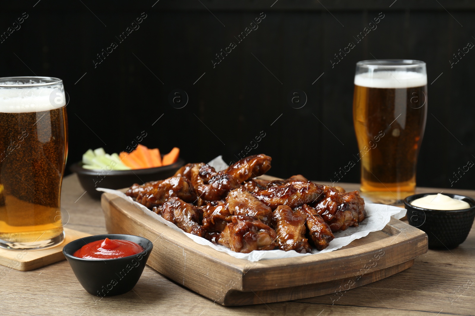 Tasty chicken wings, sauces, vegetable sticks and glasses of beer on wooden table, space for text. Delicious snacks Photo of Tasty chicken wings, sauces, vegetable sticks and glasses of beer on wooden table, space for text. Delicious snacks